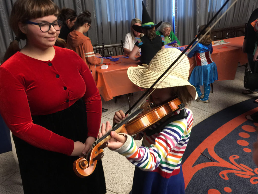 Playing violin at the instrument petting zoo at the San Antonio Symphony Halloween Spooktacular | San Antonio Charter Moms