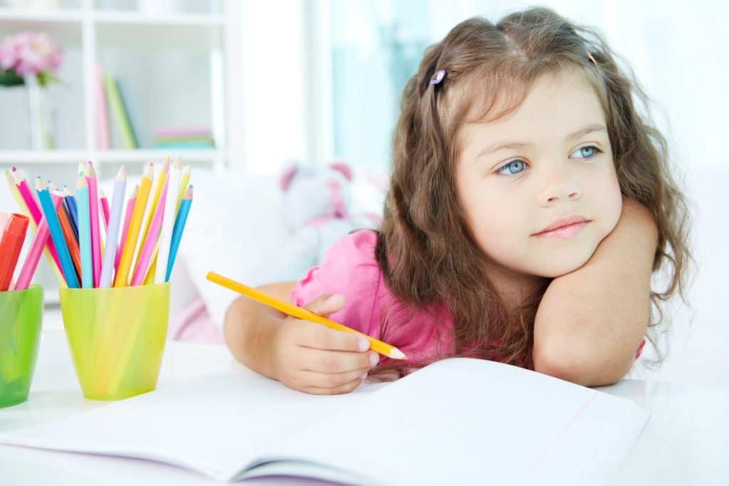 young girl holding a colored pencil over an open notebook and staring into the distance, post title "Decoding the IEP"