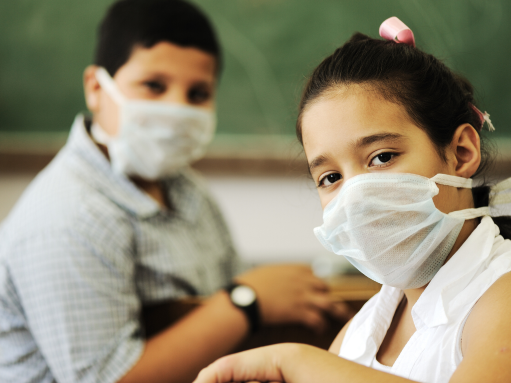 boy and girl sitting apart in classroom wearing masks