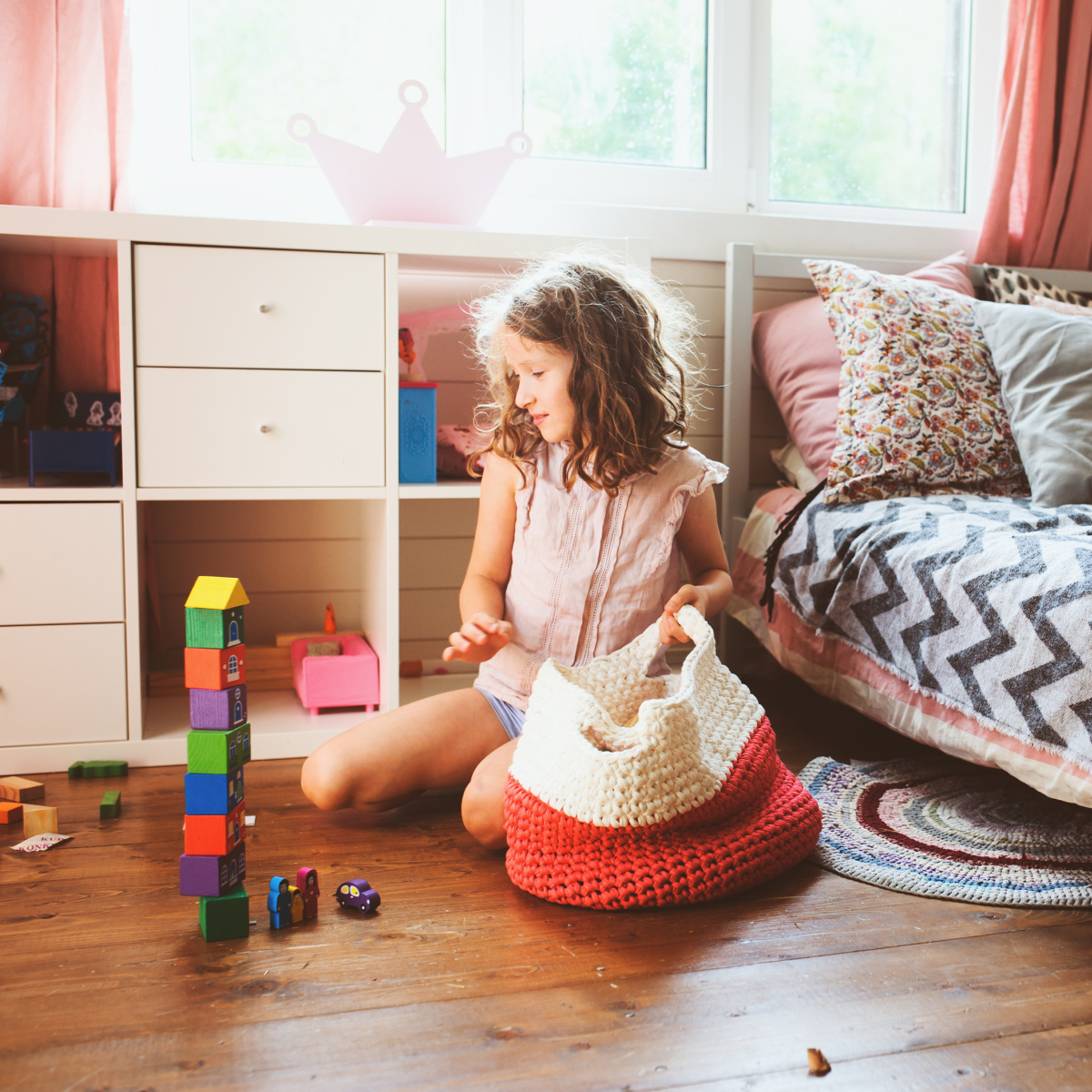 girl in bedroom with toys and a basket kids can learn organization skills for their toys, clothes, rooms