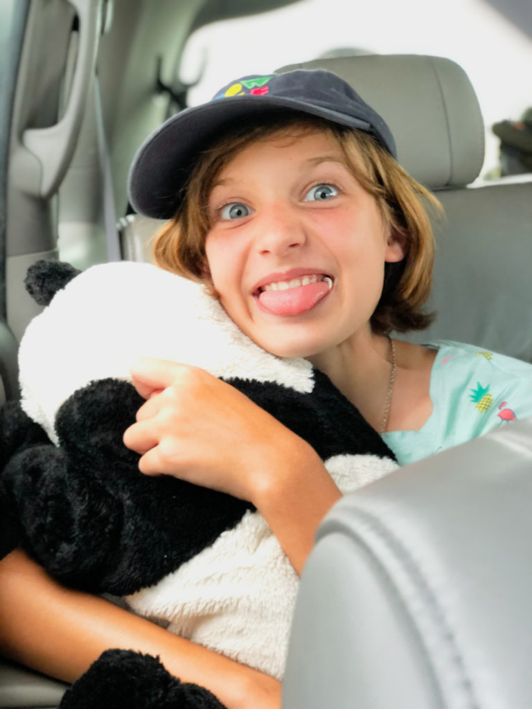 young girl making silly face in car during family road trip
