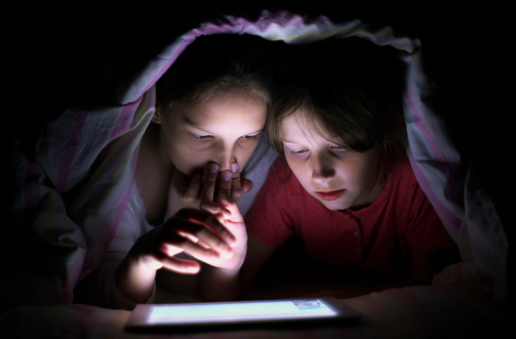 two girls in the dark looking at tablet screen | nexttalk