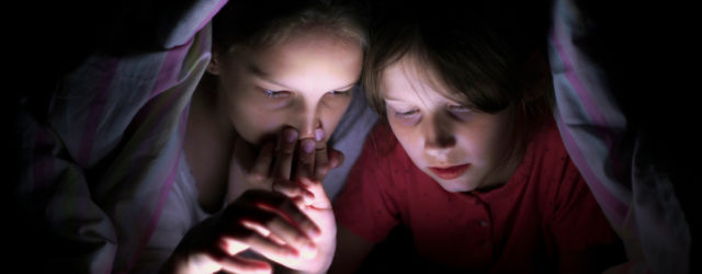 two girls in the dark looking at tablet screen | nexttalk