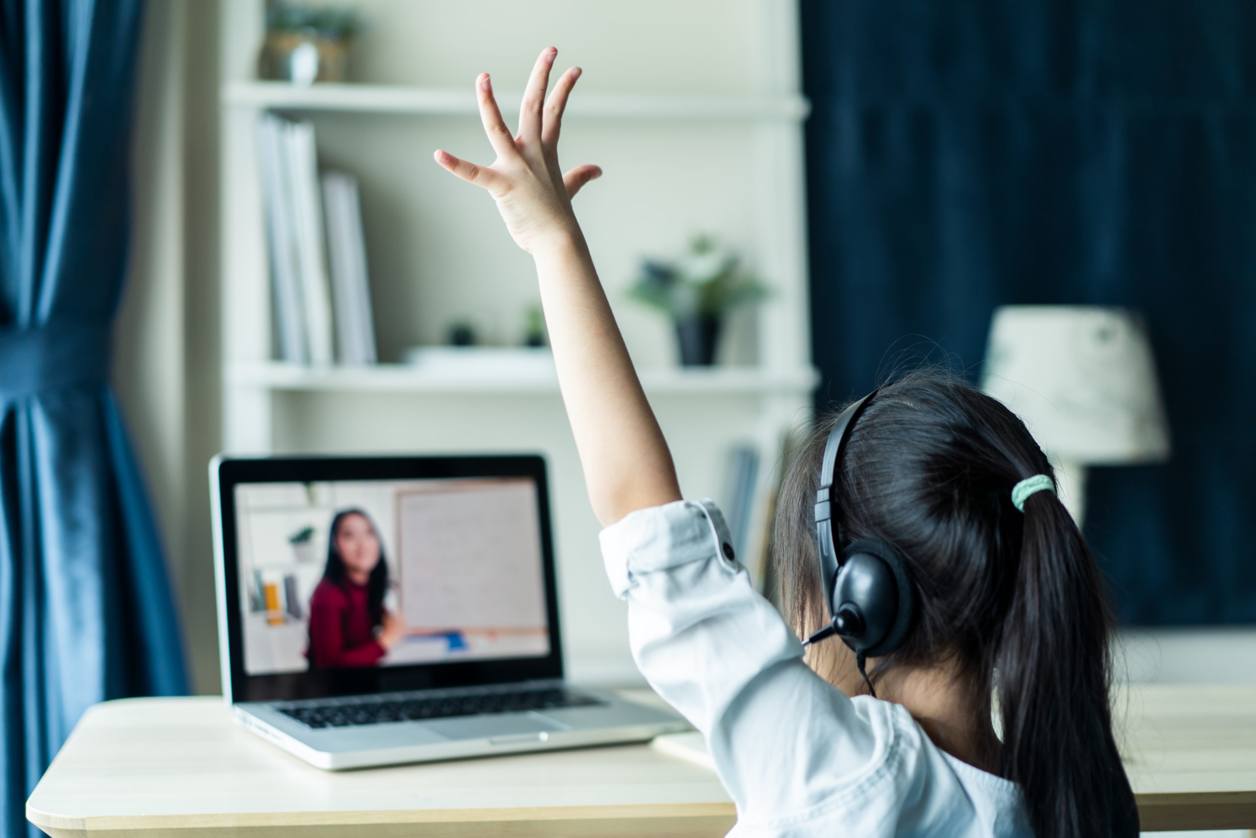 girl raising hand at computer for online private school