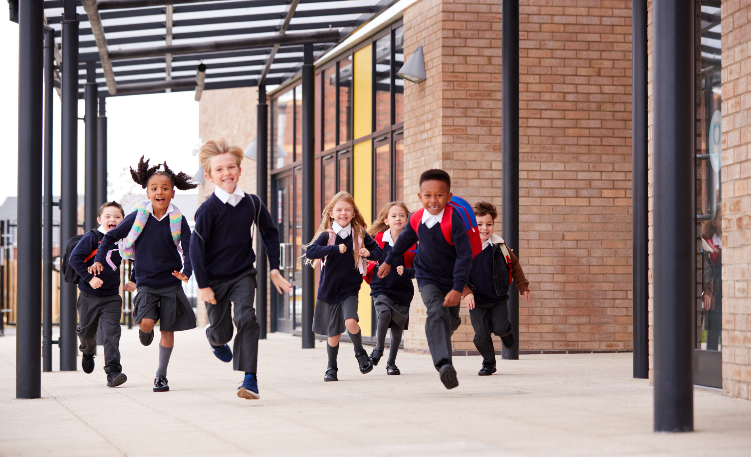 kids in school uniform running in front of school, choose to succeed quality education