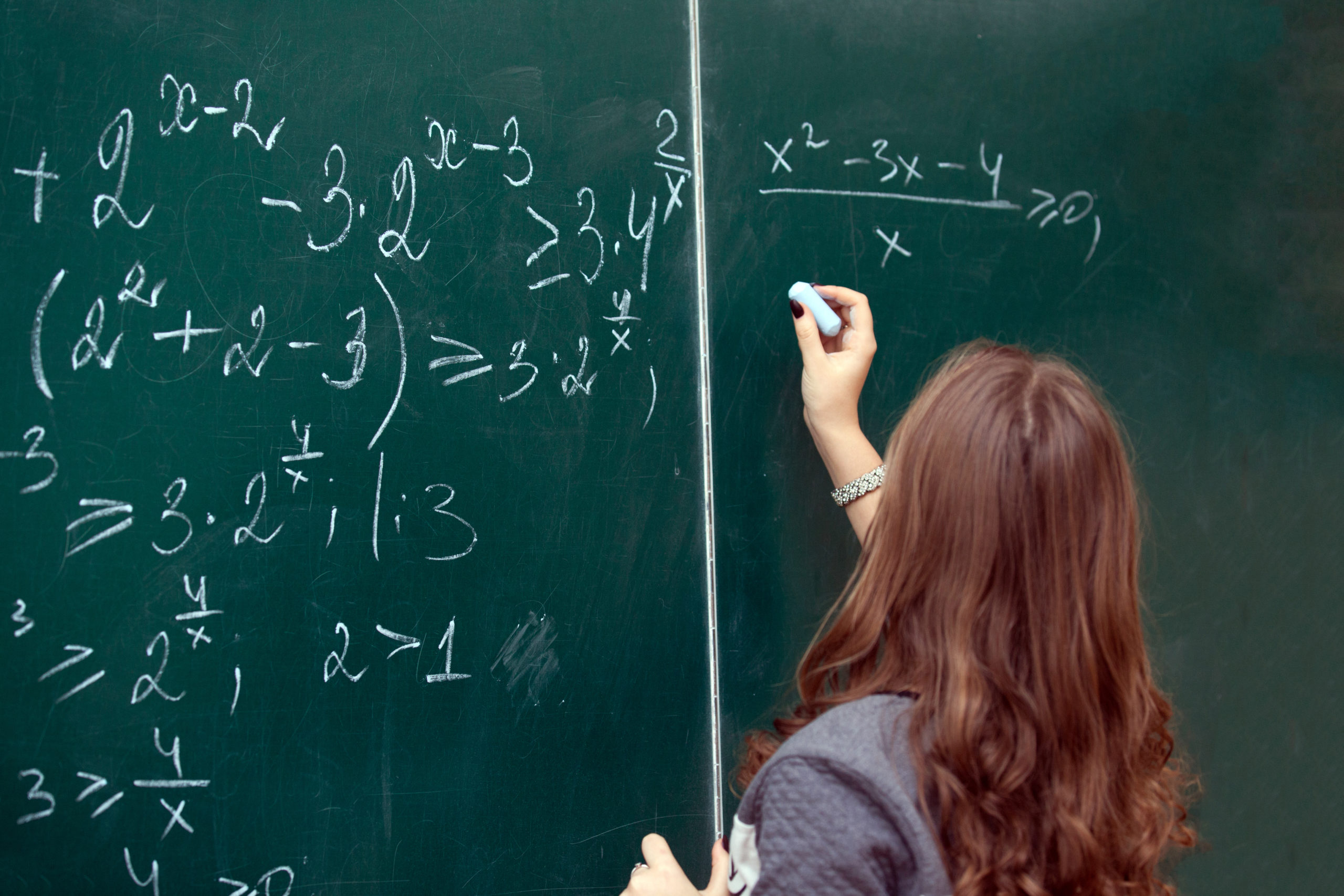 math teacher writing on chalkboard
