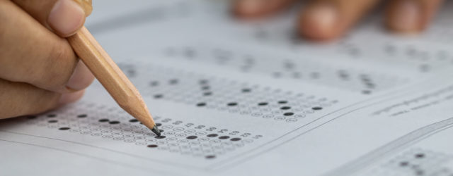 student's hands holding pencil and bubbling in answers on paper sat college test