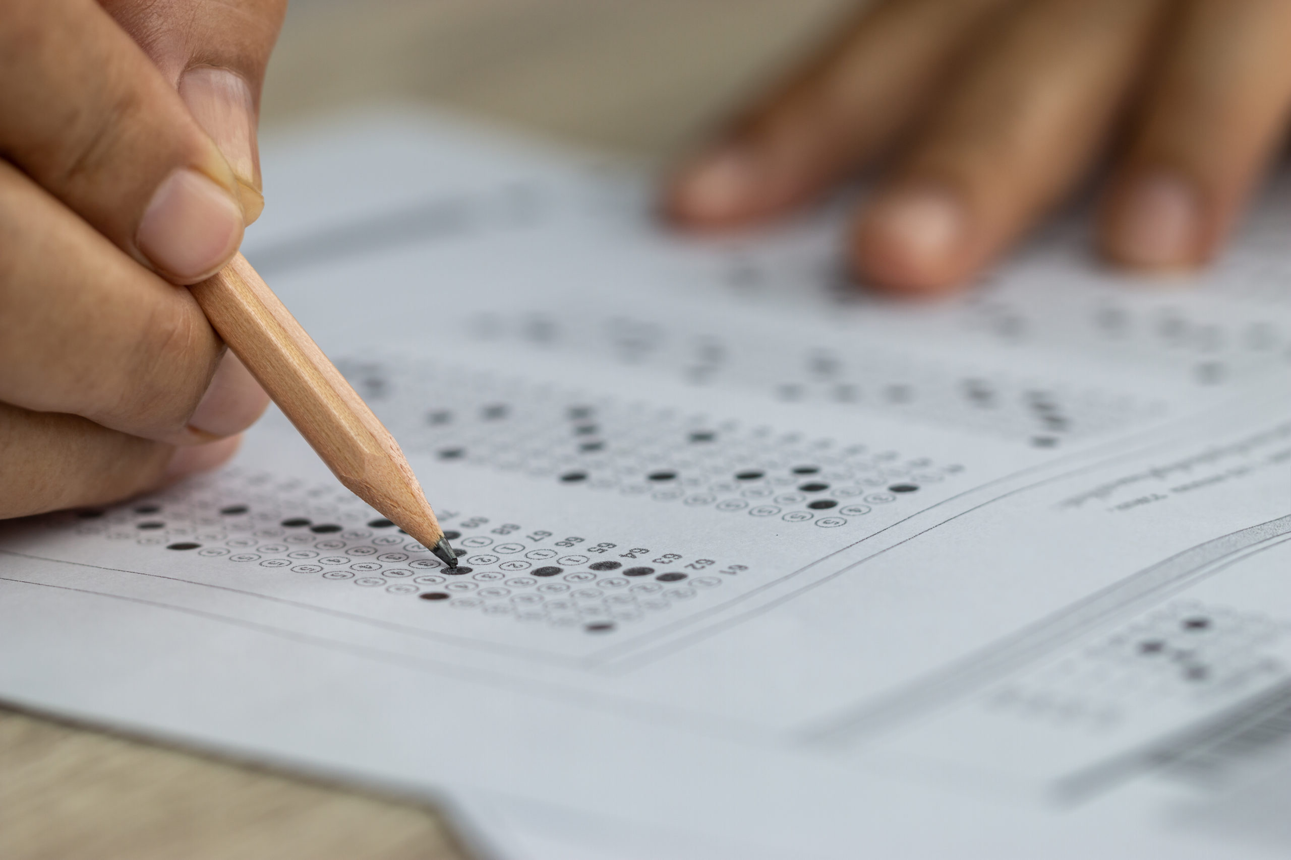 student's hands holding pencil and bubbling in answers on paper sat college test