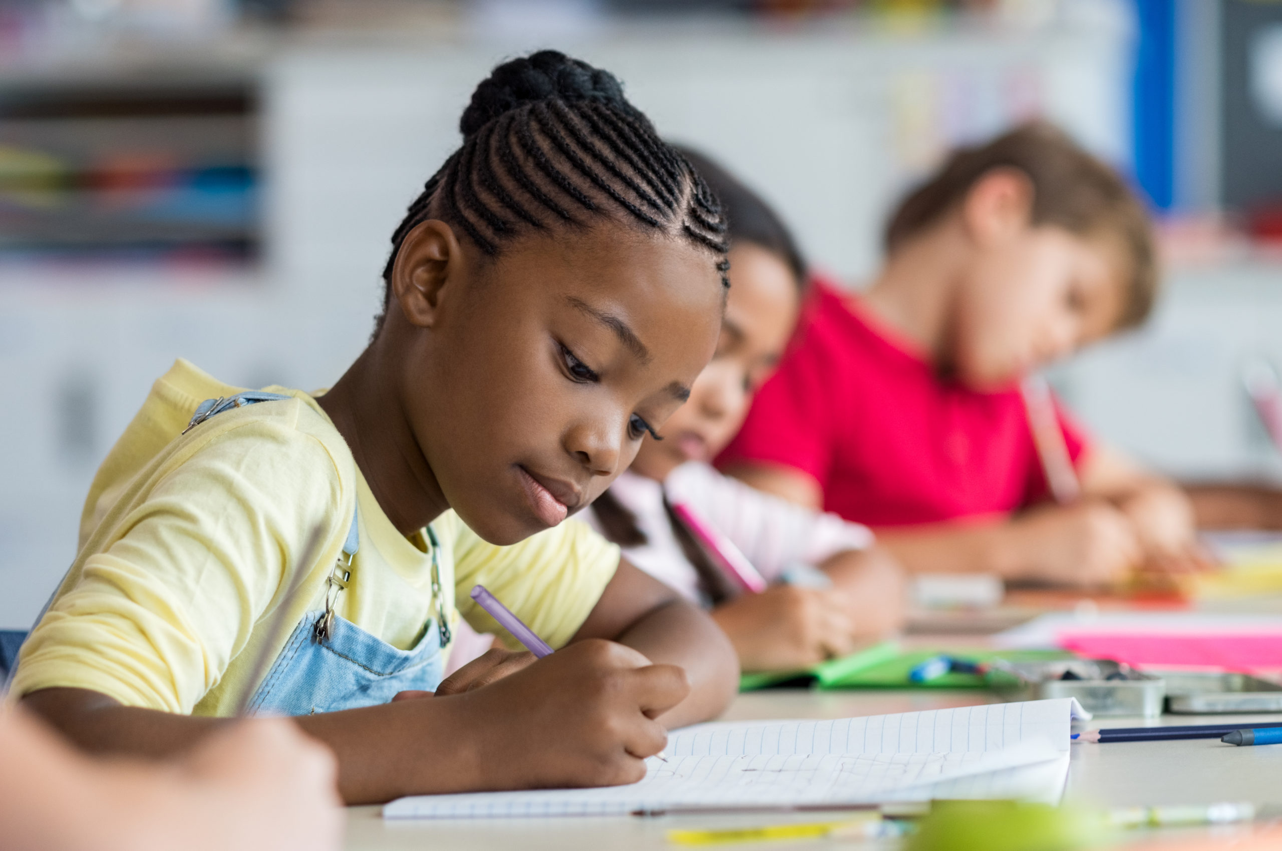 Young Black female student writing at table | Essence Prep