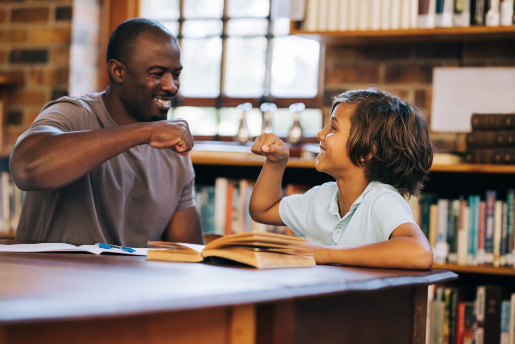 executive function coach and student giving each other a high five in a library